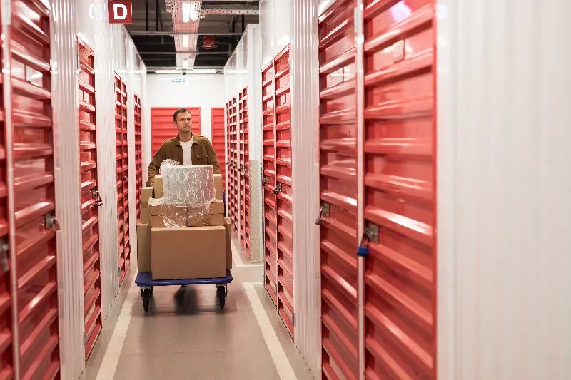 A loaded cart being wheeled down a lit storage corridor